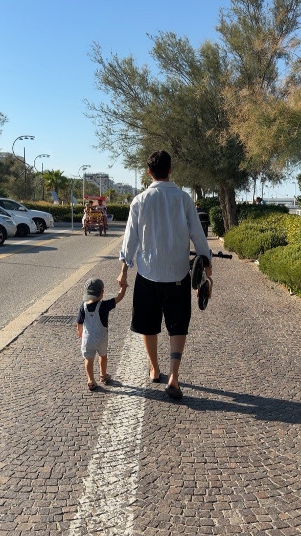 Andrea Delle Foglie passeggia tenendo suo figlio per mano